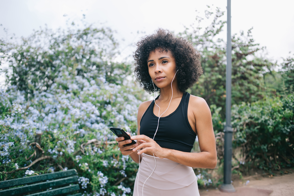 A woman listens to a story on a phone while outdoors