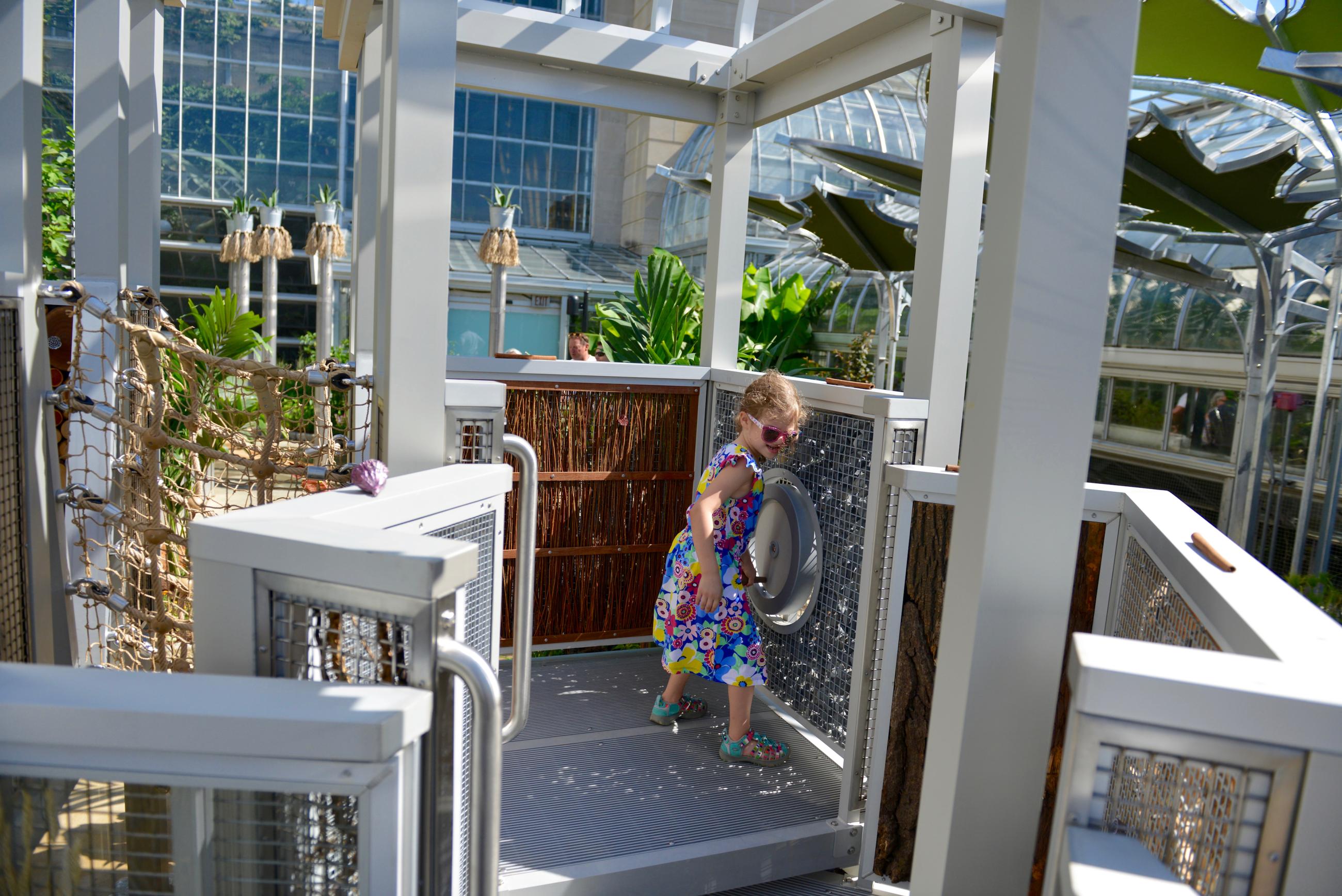 A child turns a crank in a play structure