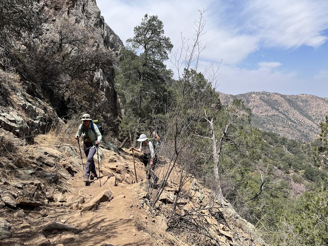 Two people hike up a dry mountain