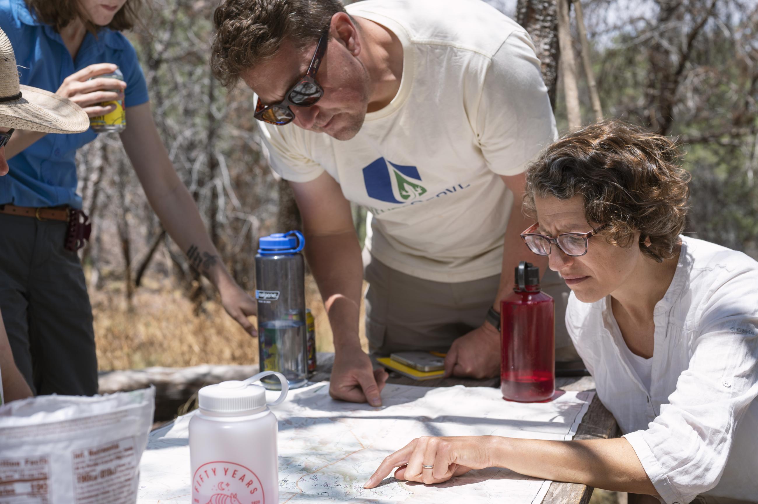 three people look at a map